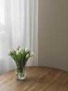 A bouquet of white tulips in a glass vase on a wooden table in the living room Royalty Free Stock Photo