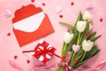 Bouquet of white tulips with red envelope and gift box on pink b Royalty Free Stock Photo