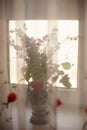 Bouquet of wild flowers on a windowsill, a view through a transparent tulle