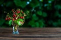 bouquet wild strawberry in transparent shot glass stays on the brown wooden table with green leafs on the back, with placeholder Royalty Free Stock Photo