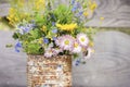 a bouquet of wildflowers of forget-me-nots, daisies and yellow dandelions in full bloom in a rusty rustic jar against a background Royalty Free Stock Photo