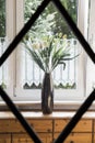 Bouquet of wildflowers, grass and bulrush in vase on windowsill