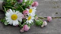 A bouquet of wildflowers lies on a wooden table.