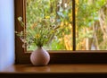 Bouquet of wildflowers in a pink vase on a wooden window sill at summer day