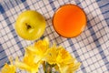 Bouquet of yellow daffodils and apple, glass of orange juice on Royalty Free Stock Photo