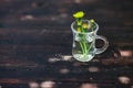 Bouquet of yellow dandelions in glass on grungy wood.