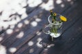 Bouquet of yellow dandelions in glass on grungy wood.