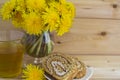 A bunch of yellow dandelions. A glass of tea in a glass mug. Two slices of honey roll with cream. Royalty Free Stock Photo