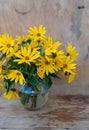 A bouquet of yellow Jerusalem artichoke flowers in a glass vase on a wooden background. Postcard with place for text. A simple Royalty Free Stock Photo