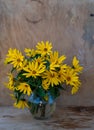 A bouquet of yellow Jerusalem artichoke flowers in a glass vase on a wooden background. Postcard with place for text. A simple Royalty Free Stock Photo