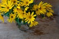 A bouquet of yellow Jerusalem artichoke flowers in a glass vase on a wooden background. Postcard with place for text. A simple Royalty Free Stock Photo