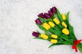 Bouquet of yellow and purple spring tulip flowers on a light stone background. Flat lay. Copy space. Mothers Day Royalty Free Stock Photo
