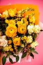 Bouquet of yellow roses, beige carnations against a pink background.