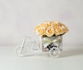 A bouquet of yellow roses in a wooden small decorative box in the form of a bicycle on a light background. Vintage Royalty Free Stock Photo