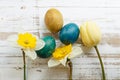 Bouquet of yellow spring tulip, daffodils and handmade colorful painted easter eggs against rustic wooden background