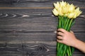 Bouquet of yellow tulip flowers in man hand on wooden background, copy space. Man holding bunch of tulips. Holiday greeting card. Royalty Free Stock Photo