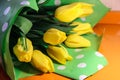 Bouquet of yellow tulips on an orange table. Flowers in the green box with white polka dots Royalty Free Stock Photo