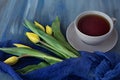 Bouquet of yellow tulips and tea on a blue textural background Royalty Free Stock Photo