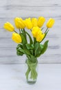 Bouquet of yellow tulips in a vase on a white wooden board Royalty Free Stock Photo