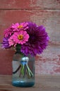 A bouquet of zinnias and dahlias in a blue canning jar with a re Royalty Free Stock Photo