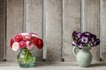 Bouquets of pansy and daisy flowers in ceramic vases. Wooden background