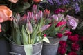 Bouquets of pink roses and red tulips in large zinc buckets for sale in store