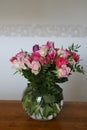 Bouquets of roses, cloves and tulips in vase on table with white and grey background