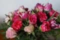 Bouquets of roses, cloves and tulips in vase on table with white and grey background