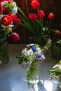 Bouquets of tulips, cherry blossoms and muskari flowers in glass jars on kitchen table