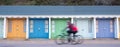 Bournemouth UK. People cycling in front of colourful beach huts located on the promenade on the Bournemouth sea front. Royalty Free Stock Photo