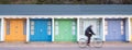 Bournemouth UK. Person cycling in front of colourful beach huts located on the promenade on the Bournemouth sea front. Royalty Free Stock Photo