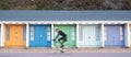 Bournemouth UK. Person cycling in front of colourful beach huts located on the promenade on the Bournemouth sea front. Royalty Free Stock Photo