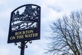Bourton On The Water SIgn stands against cloudy blue sky