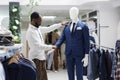Boutique assistant checking mannequin dressed in menswear latest collection