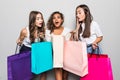 Black friday concept. Portrait of funky positive three mixed race having many colorful bags isolated on gray background
