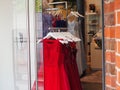 Boutique store window display with an array of vibrant red dresses suspended from a sleek metal rack