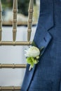 BoutonniÃÂ¨re on grooms jacket hanging over a chair at wedding reception