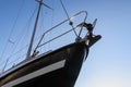 Bow of a black sailing yacht from below against the blue sky, co