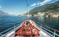 Boat tour: Boat bow, view over azure blue water, village and mountain range. Lago di Garda, Italy Royalty Free Stock Photo