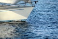 The bow of a glassfiber yacht plows over a calm sea surface