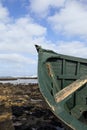 Bow of a green wooden row boat on a rocky watery shore Royalty Free Stock Photo