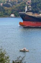 The bow of a large cargo ship sailing along the shore of the Bosphorus and a small boat Royalty Free Stock Photo