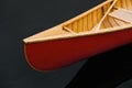 Bow nose of a red canadian canoe. Wood canoe boat on dark water