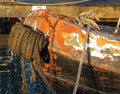 The bow of an old rusty iron canal boat moored with ropes on a jetty with reflections in dark water Royalty Free Stock Photo