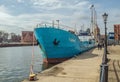 Bow of an old small blue cargo ship Tanais mooring in harbor in the Old Town of Gdansk under clouds