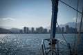 Bow of Sailboat Approaching land with city and mountains. Travel and adventure concept