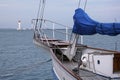 Bow of a white sailing yacht against the blue sea with anchor at the bow. lighthouse at the back side Royalty Free Stock Photo