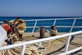 Bow of white yacht on background of blue sea.Thick anchor rope is wound around the bollards. Steel railings-fences. Royalty Free Stock Photo