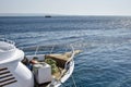 Bow of white yacht. Bay with thick rope lies on wooden deck. Rope is wound on mooring post of yacht. A moored yacht. Copy space. Royalty Free Stock Photo