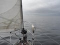 Bow of yacht sailing in calm water towards small islands under heavy cloudy sky Royalty Free Stock Photo